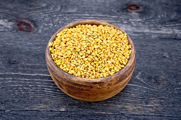 Fenugreek in clay bowl on wooden board