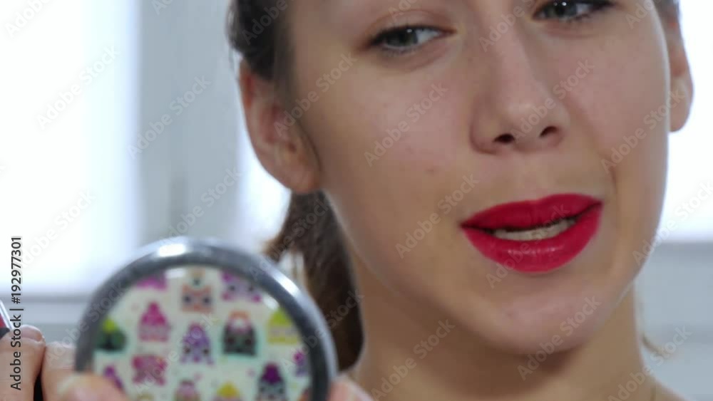 Poster young and smiling woman putting lipstick