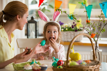 Mother and daughter celebrating Easter, eating chocolate eggs. Happy family holiday. Cute little...