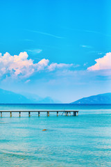 Beautiful landscape view of summer lake Garda in Italy with turquoise water and amazing pink sunset evening clouds