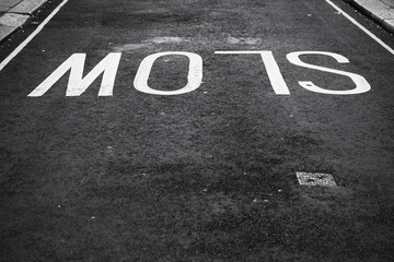Slow, white text road marking over asphalt