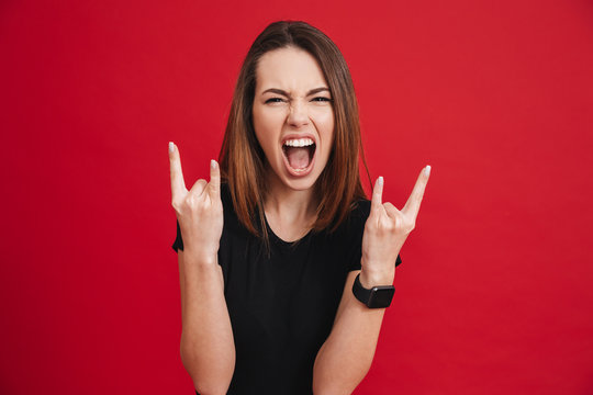 Portrait of a screaming girl showing horns up gesture