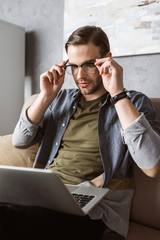 handsome stylish man working with laptop on couch