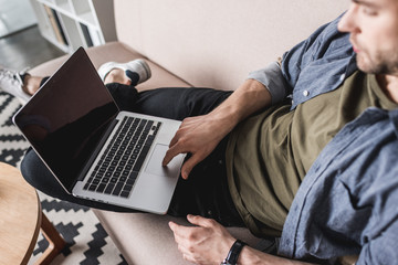 close-up shot of handsome man working with laptop on couch