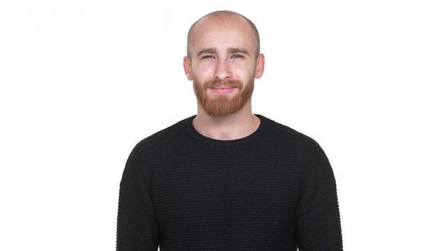 Portrait of positive man in black sweatshirt expressing acceptance, while nodding over white background in studio. Concept of emotions