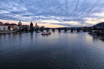 Charles bridge and river Vltava with some boats in the evening