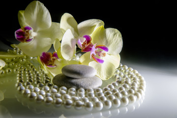 flat stones on a white glass on the background of yellow orchids 