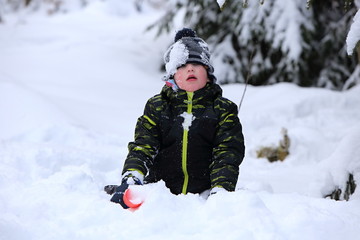Fototapeta na wymiar Kid playing in deep snow with red shovel