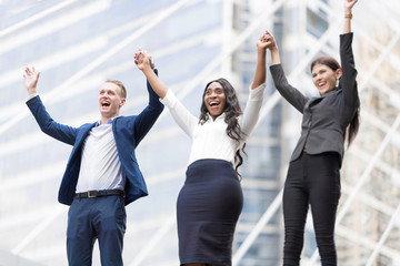 Successful Business Teamwork.Happy Young Businessmen Rising Hands Up while Their Female Colleague Smiling to Sky.