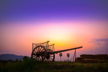 Silhouette of the old vintage wood cart over the colorful sky in the morning in Thailand.