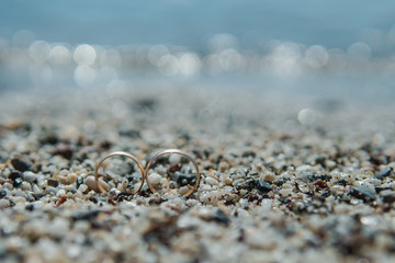 wedding rings on the pebble sand on the beach