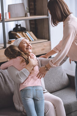 mother and daughter visiting sick smiling grandmother in kerchief