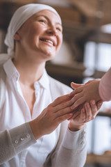Obraz premium cropped shot of child and smiling sick mature woman in kerchief holding hands