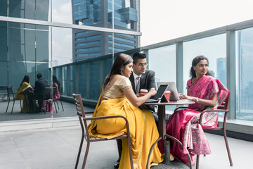 Three Indian business people with worried facial expression talking during break at work