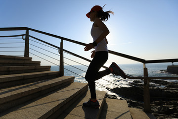 sporty fitness female runner running upstairs on coast trail