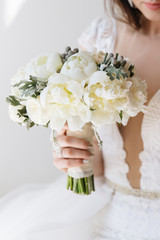Bride in a white wedding dress holding tender bouquet. Bridal boudoir.