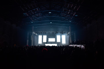 People on the dance floor during a concert in a hangar. Five white led wall ideal to insert text or...