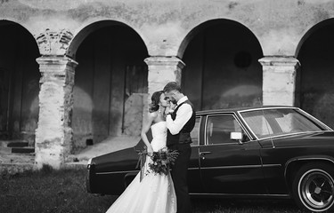 wedding black and white portrait of the bride and groom on the background of the old car