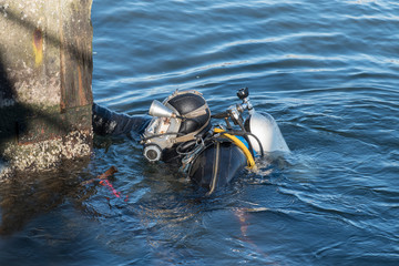 industrial diver with scuba gear, diving helmet and protective suit working in the water at the...