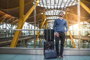 young handsome man unhappy upset  at the airport waiting his delayed flight with luggage