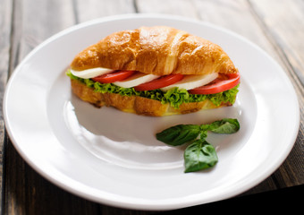 Fresh croissant with ham and salad