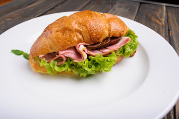 Fresh croissant with ham and salad