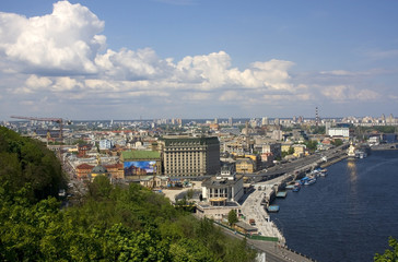 Kiev, the capital of Ukraine areal view with cloudy sky over river Dnieper, old historical district Podil with river port and modern buildings at the left bank of the river on the background.