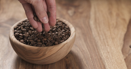 man hand check coffee beans in bowl on table