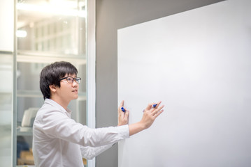 Young Asian man writing on white board in conference room. Business meeting presentation concept