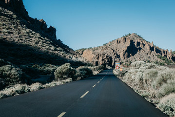 Highway goes through the rocks with green plants. Teide National Park. Tenerife