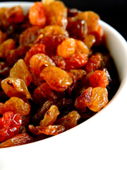 Golden raisins in a white bowl. Close up.
