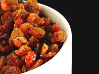 Golden raisins in a white bowl. Close up.