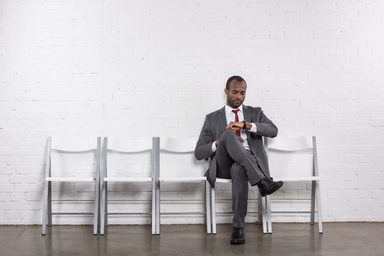 african american businessman checking time while waiting for job interview