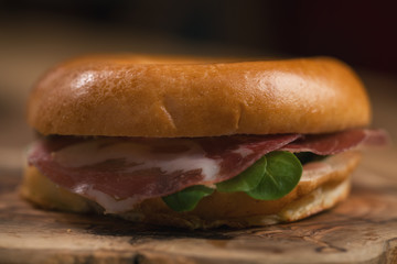 bagel with coppa and cream cheese on wood boar