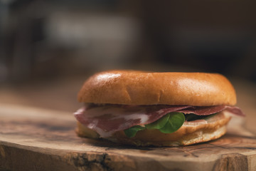 bagel with coppa and cream cheese on wood boar