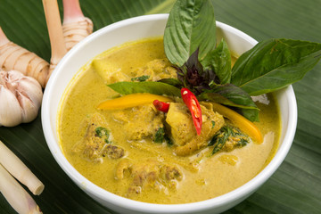 Green Curry With Chicken in bowl with galangal and lemon grass on banana leaf