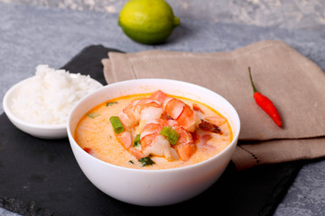 A bowl of fish soup with salmon, shrimps and potato at natural white background