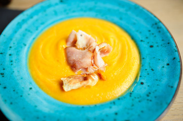 Vegan Creamy Delicious Pumkin Soup with fresh vegaetables over a wooden background.