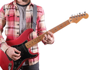 Obraz premium Casually dressed young man with guitar playing songs isolated on white. Laptop on table. Online guitar lessons concept. Male guitarist practicing chord grips.