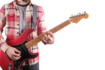 Casually dressed young man with guitar playing songs isolated on white. Laptop on table. Online guitar lessons concept. Male guitarist practicing chord grips.