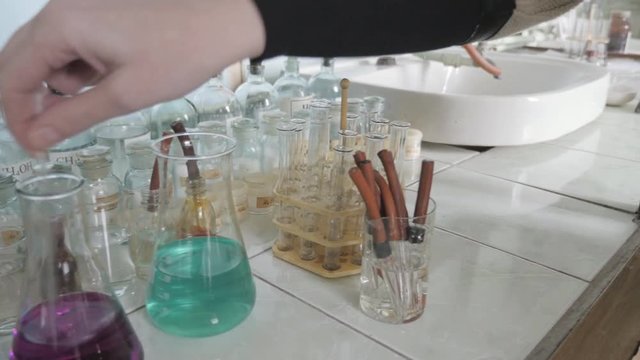 The researcher stirs colored liquid in flask for study the chemical reaction
