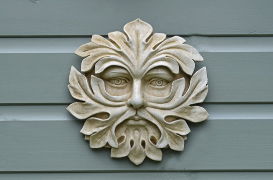 A pottery head of the Green Man on a garden wall