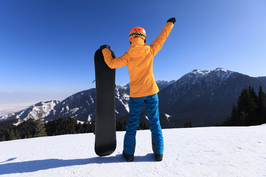 successful snowboarder with snowboard on winter mountain top