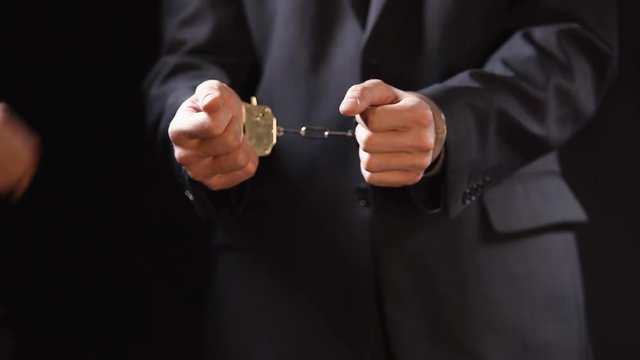 Public official handcuffed, charged with bribery, political corruption, closeup