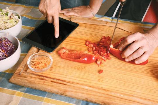 Couple cooking dinner using a digital tablet in kitchen