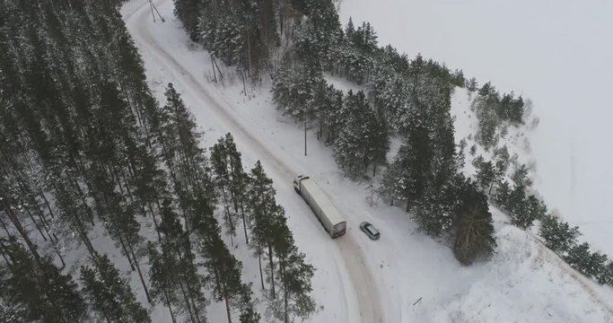 Truck driving on winter country road in snowy forest. Aerial footage.