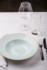 Empty plate, fork, knife and wine glasses on white table