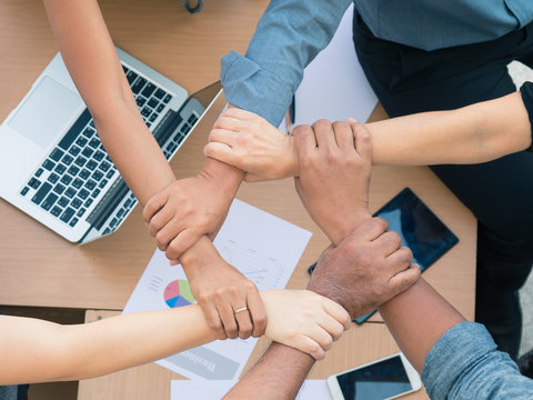 Team work concept; close up of joining hands of businessman in unity cross processing background; Expression for cooperation