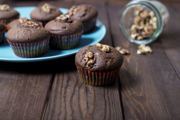 on a wooden background is a blue plate with chocolate cakes and nuts.