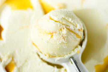Vanilla ice cream scoop background. Summer food concept, copy space, top view. Scooped texture. Scooping out yellow mango ice-cream.